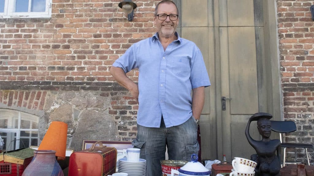 Brukt- og antikkselger Bjørn Glenge Tangen foran bord med retro gjenstander.