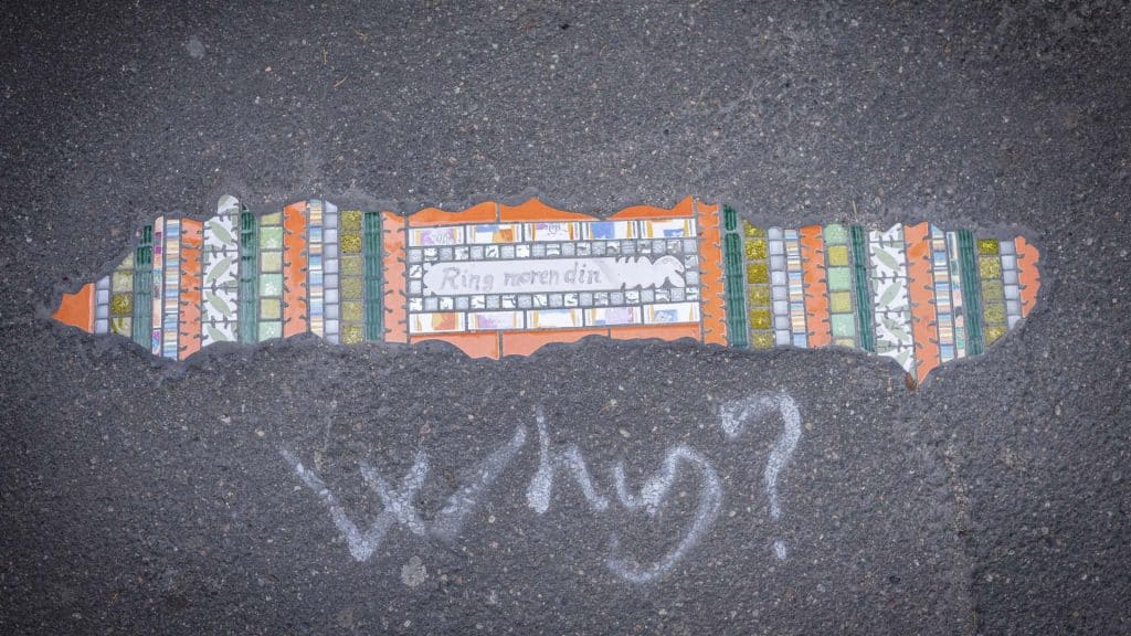 Gatekunst i form av mosaikkfelt lagt ned i asfalt, med teksten «Ring moren din» og fargerike mønstre.