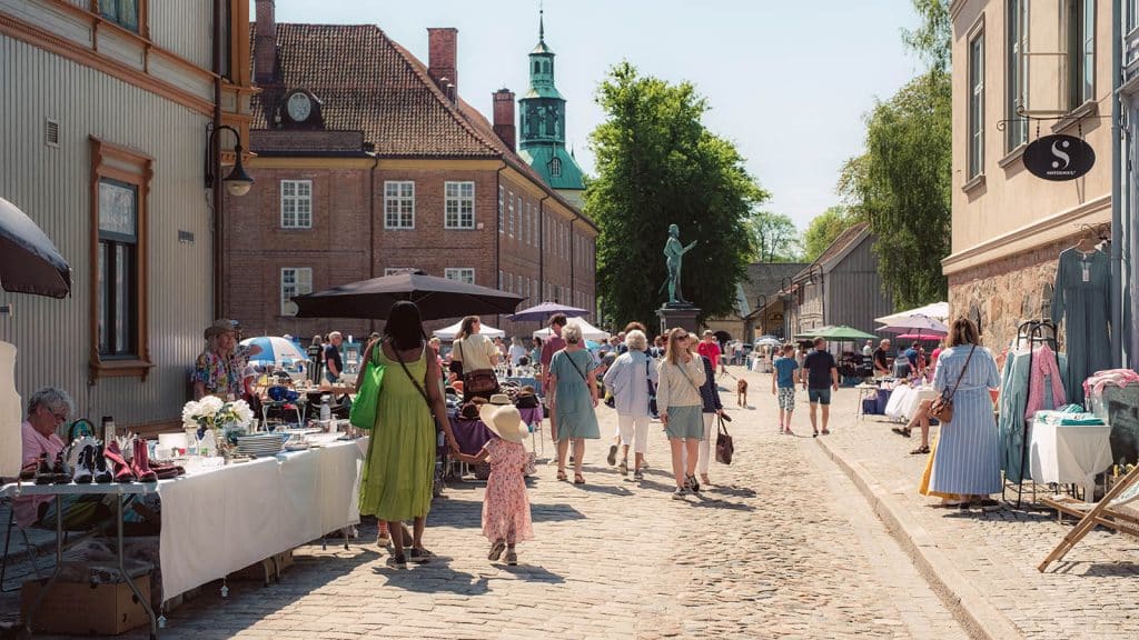 Folk rusler mellom salgsboder langs brosteinsgate i Gamlebyen, Fredrikstad