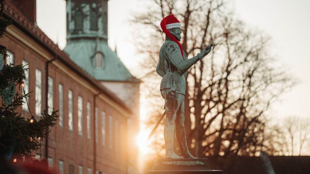 Statue av Frederik 2. med nisselue i solnedgang i Gamlebyen Fredrikstad.