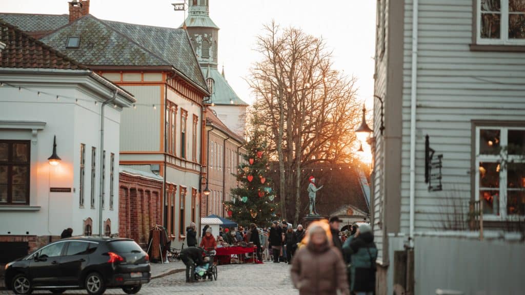 Oversiktsbilde av julemarked med folkeliv, pyntet juletre og statue med nisselue i Gamlebyen Fredrikstad.