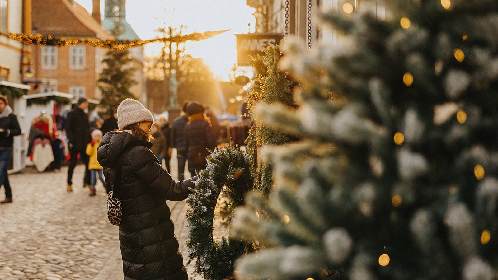 Person i vinterklær som ser på julekrans på julemarked i Gamlebyen.