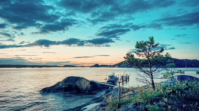 Utsikt over svaberg, sjø og småøyer i kveldssol på Søndre Sandøy.