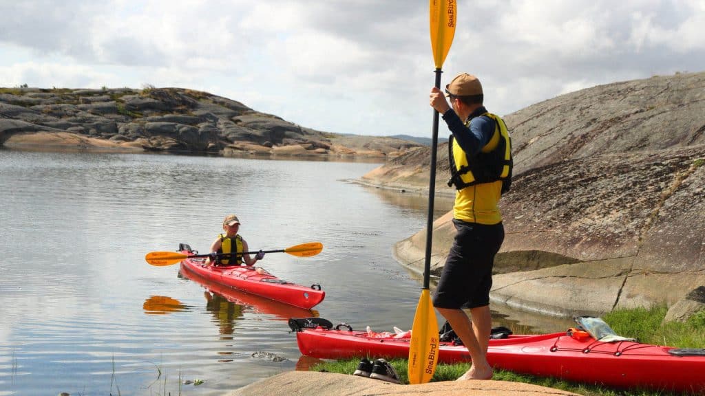 Kajakker er snart på land mellom svaberg ved lavvann, med utsikt mot havn og svaberg i det fjerne.
