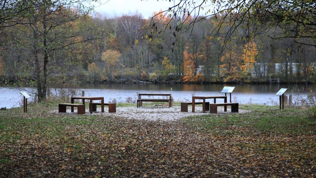 Utsikt over Glomma fra rasteplass med benker og informasjonsplakater.