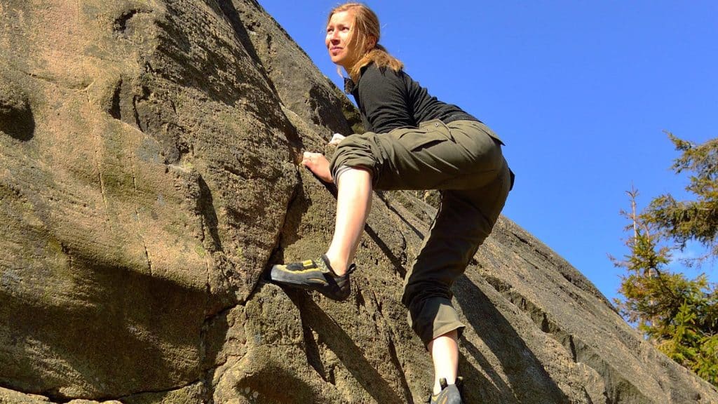 Kvinne buldrer på fjellvegg ved Guttormsvauen i solskinn.