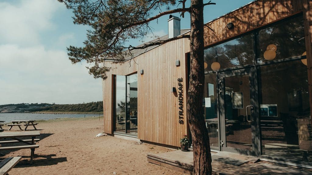 Strandkafé og besøkssenter ved sandstranda på Storesand, omgitt av furutrær og kystlandskap.