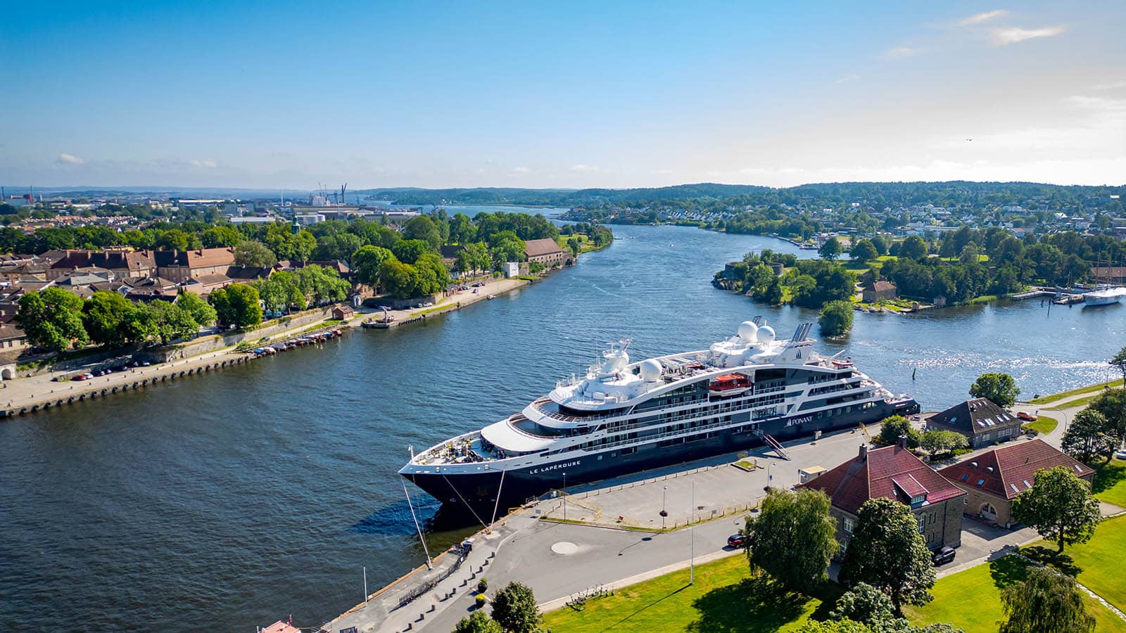 Wide-angle view of a cruise ship at the quay in Fredrikstad, with river mouth and green surroundings