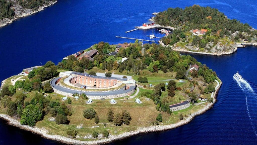 Luftfoto av Oscarsborg festning på en øy i Oslofjorden, omgitt av skog og blått vann.