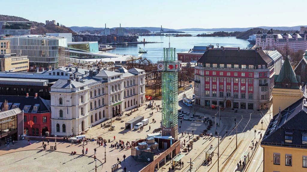 Utsikt over Jernbanetorget i Oslo med fjorden, Operaen og byens moderne arkitektur i bakgrunnen.